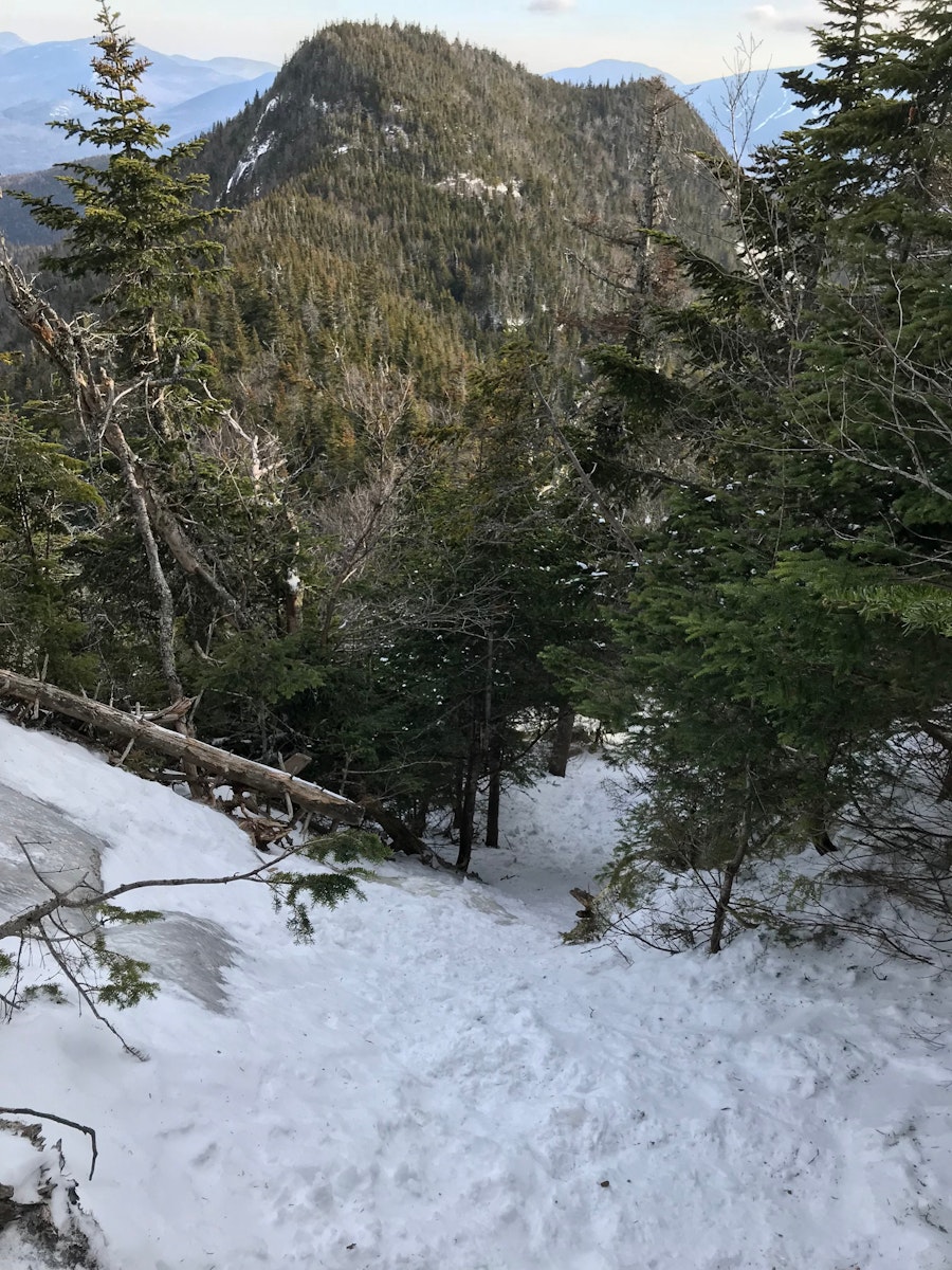 A steep snow and ice covered trail in the tree covered mountains of the Adirondacks.