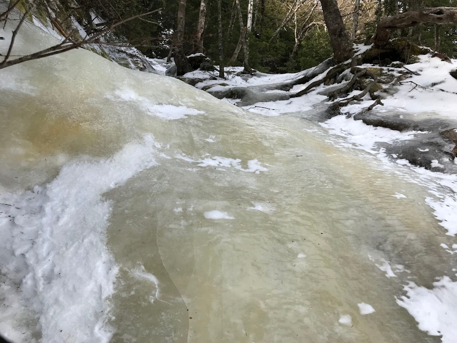 A steep snow and ice covered trail in the tree covered mountains of the Adirondacks.