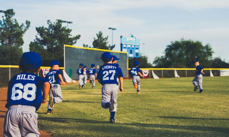 A team of little boy baseball players runs out onto the field.
