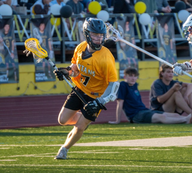 Two opposing boys lacrosse players attacking and defending.