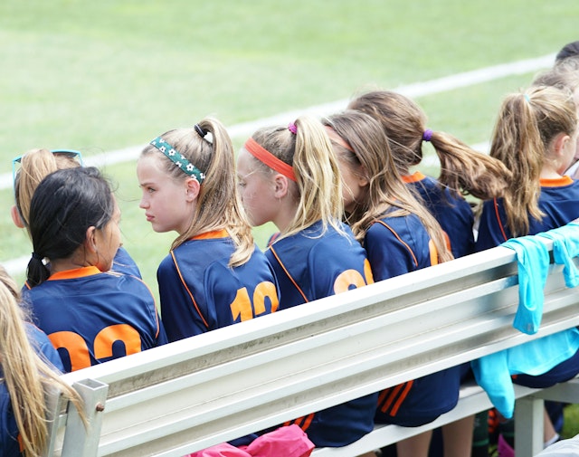 A team of young girls wearing matching uniforms waiting to take the field.